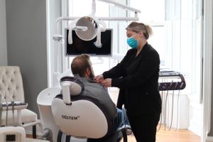 Dental professional assisting a patient in a modern dental office setting, preparing for teeth whitening treatment.